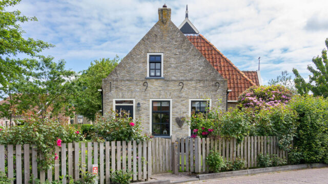 Color photo of European rural stone cottage and garden.