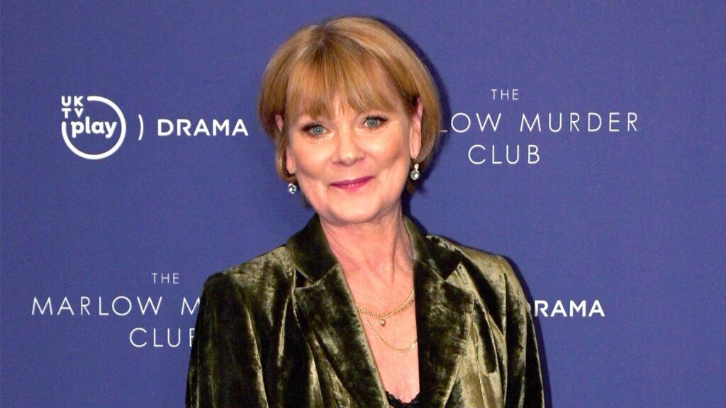 Head and shoulders of Samantha Bond smiling in front of a blue background that says The Marlow Murder Club.